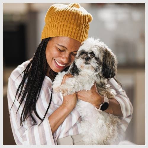 A happy dog sitter cuddling a dog.
