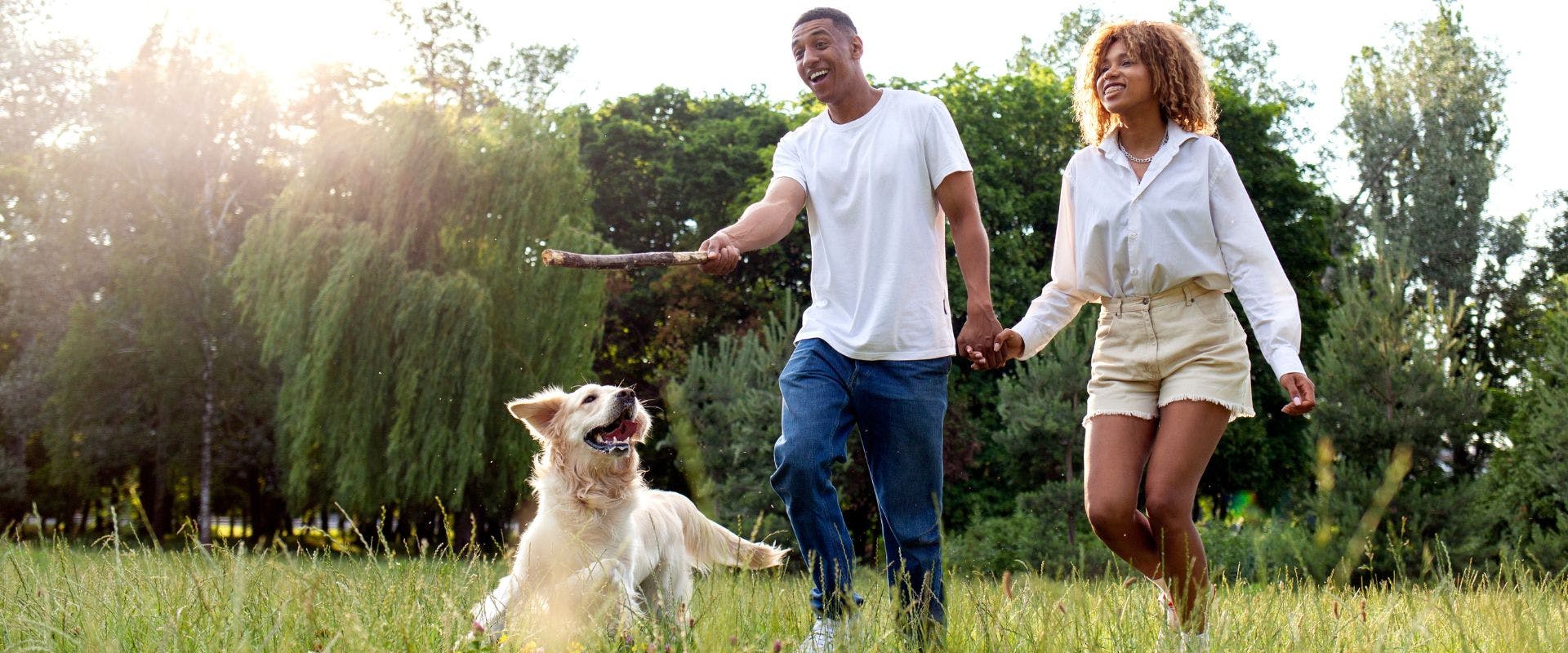 Couple playing fetch with a Golden Retriever